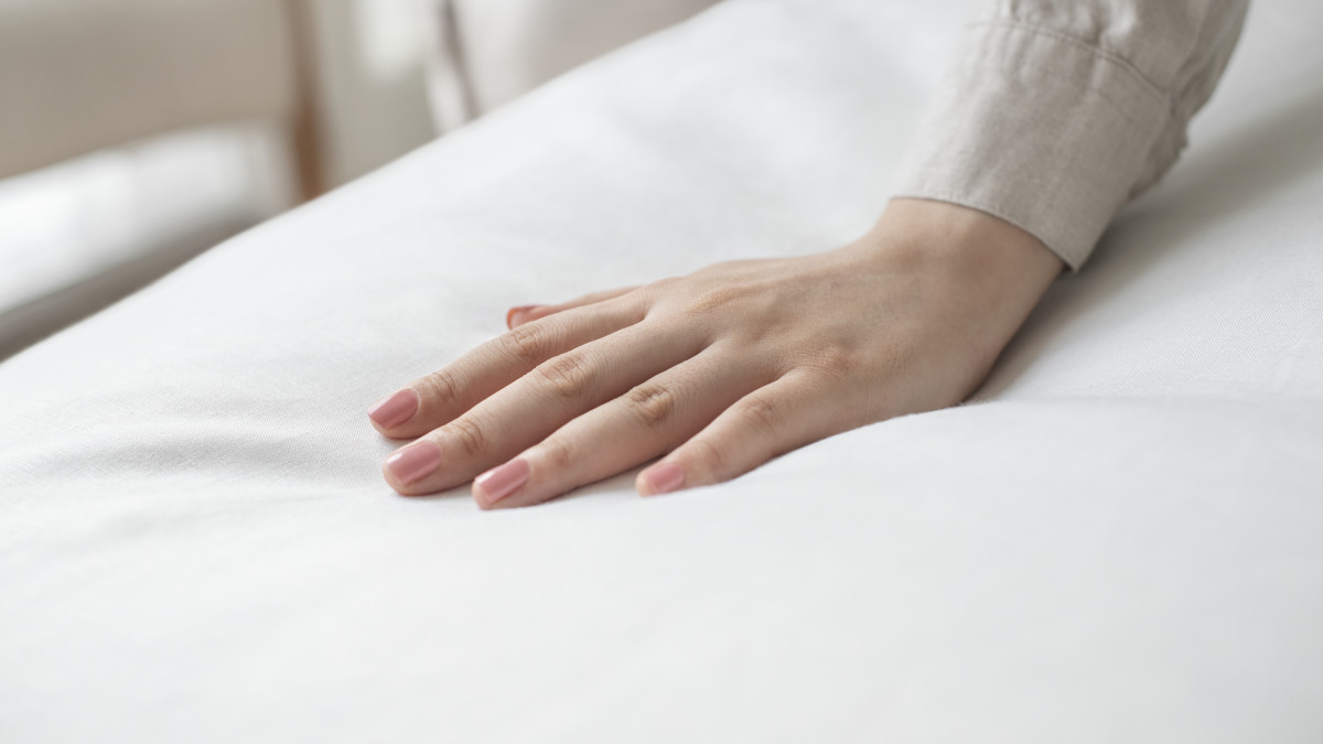 une main posée sur un matelas en fibre naturelle