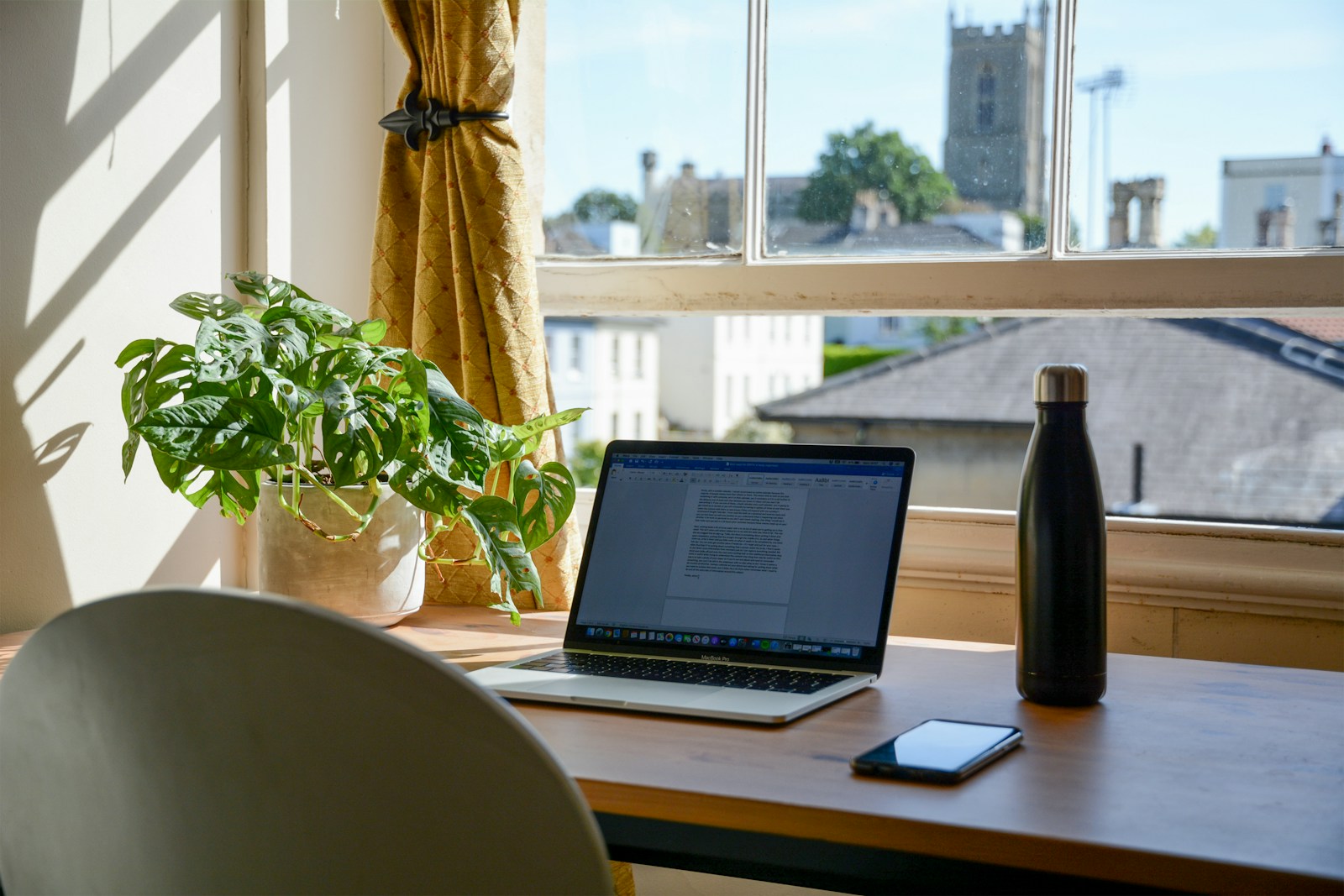 Bureau en bois placé près d'une fenêtre, avec une plante.