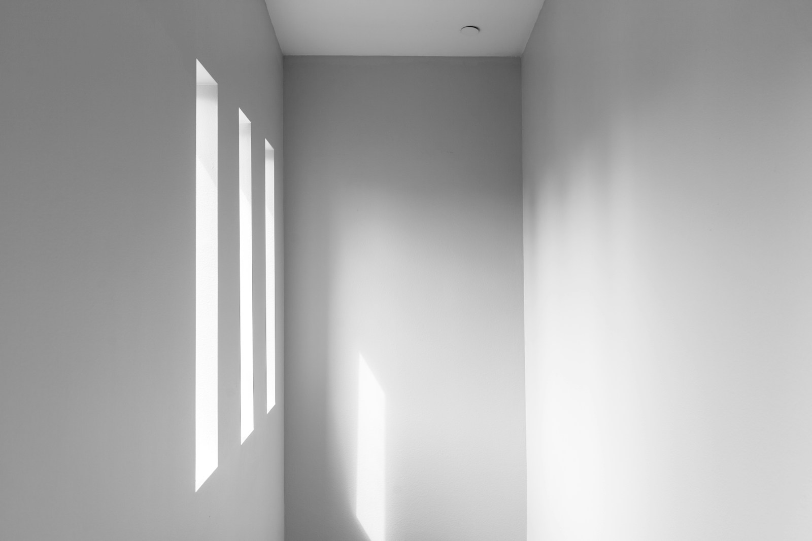 Cage d'escalier vide et lumineuse, éclairée par une fenêtre haute.