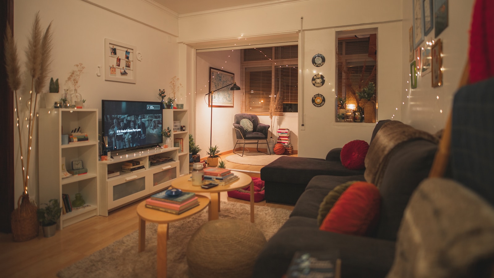 Canapé bas beige orienté vers un écran de télévision dans un salon éclairé chaudement.