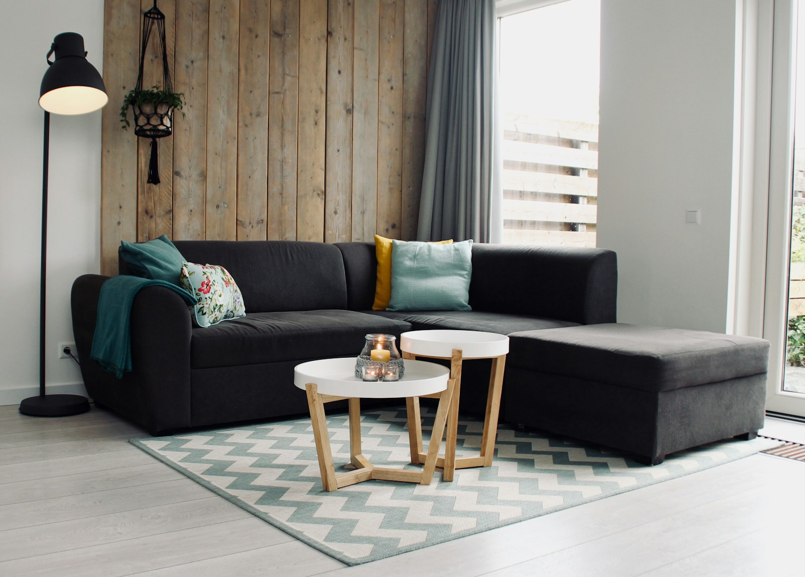 Canapé d'angle clair installé dans un coin de petit salon, avec tapis et plantes.