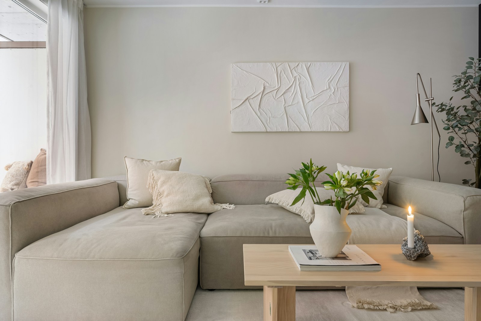 Canapé en lin, coussin en laine bouclée et tapis en jute dans un salon clair