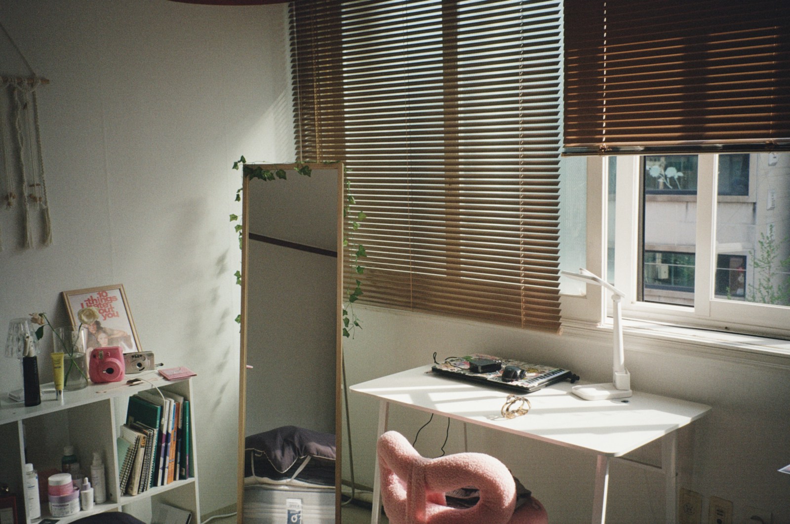 Chambre d'adolescent avec bureau, chaise et étagères éclairée par la fenêtre