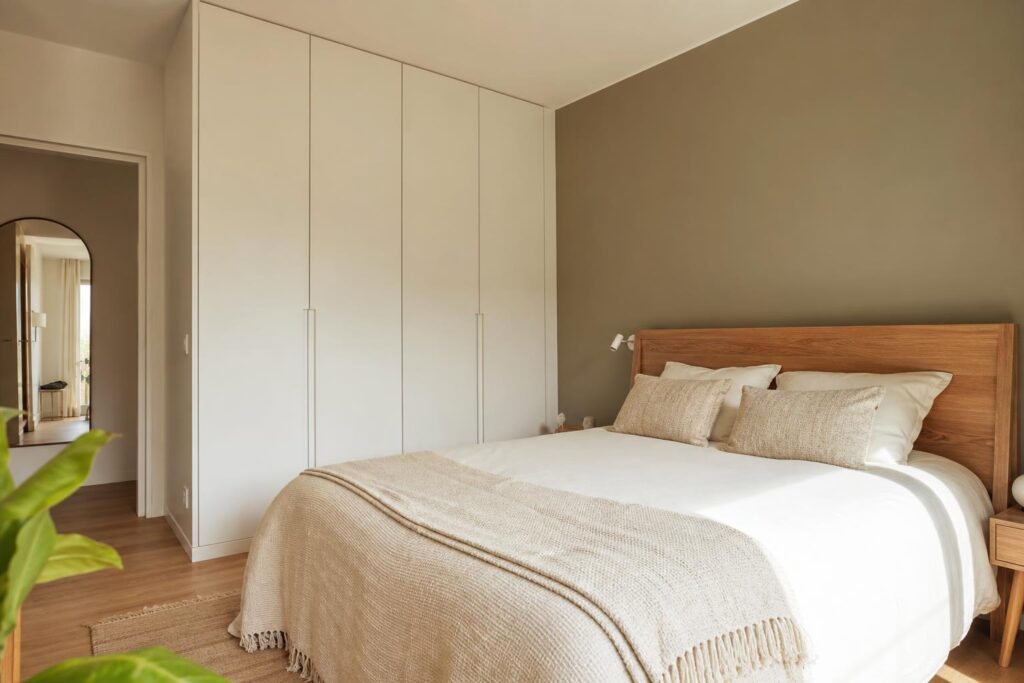 Chambre de 9 m² avec lit double, tête de lit en bois et placard toute hauteur baigné de lumière naturelle.