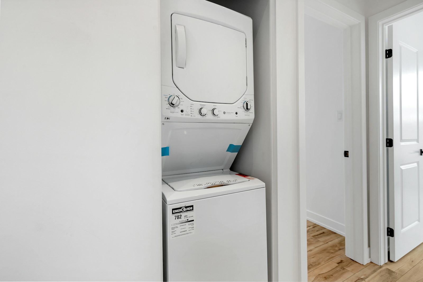 Colonne lave-linge et sèche-linge empilés dans une buanderie étroite.