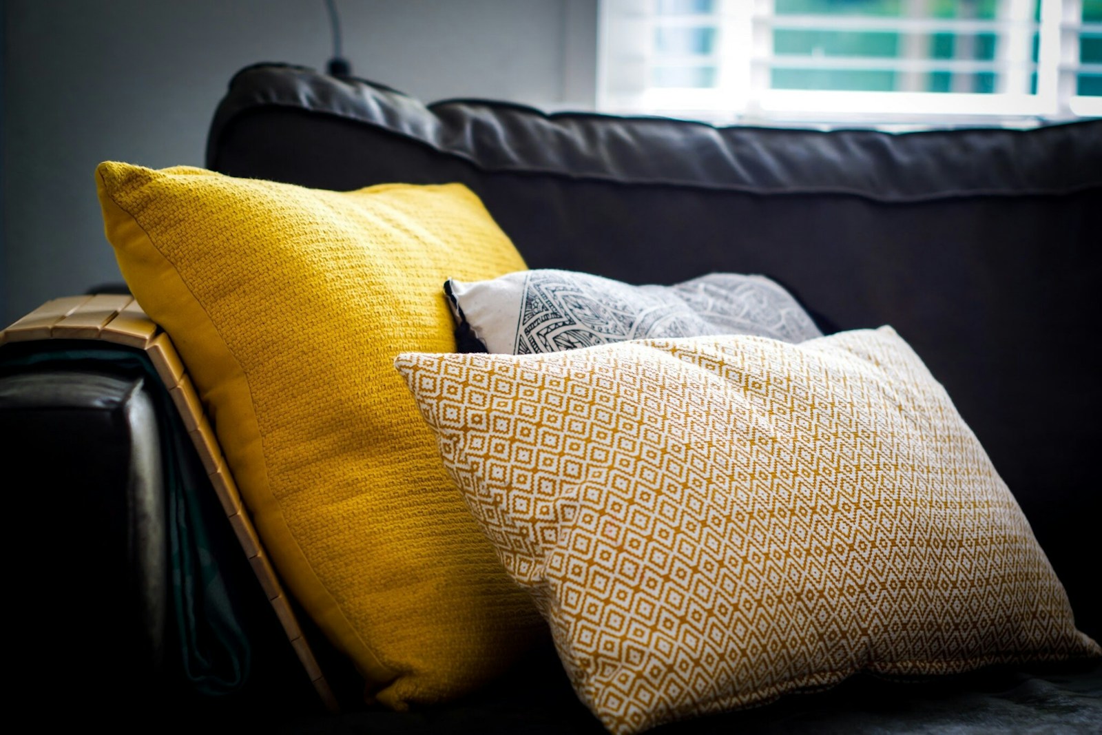 Coussin jaune ocre posé sur un canapé en velours aubergine.