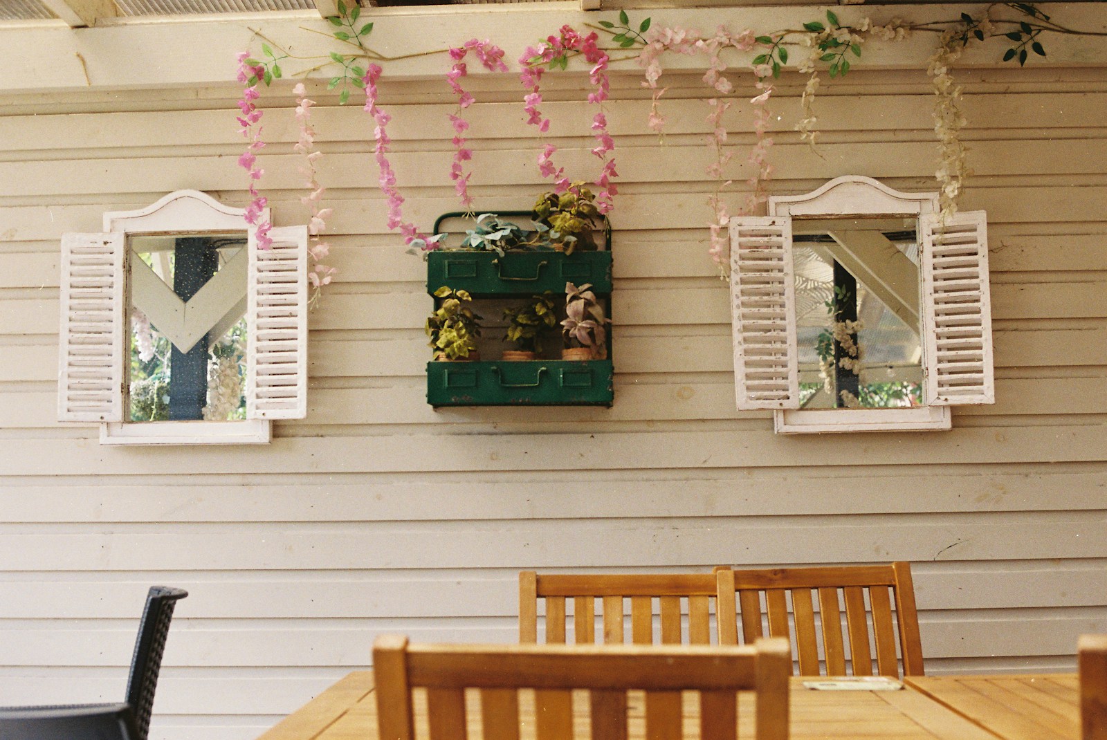 Décoration murale extérieure avec miroir et paniers tressés sur un mur de terrasse.