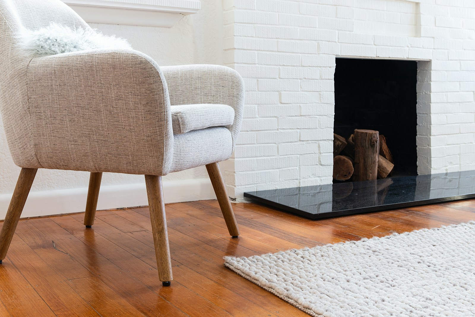 Fauteuil confortable et tapis installés à côté d'une cheminée.