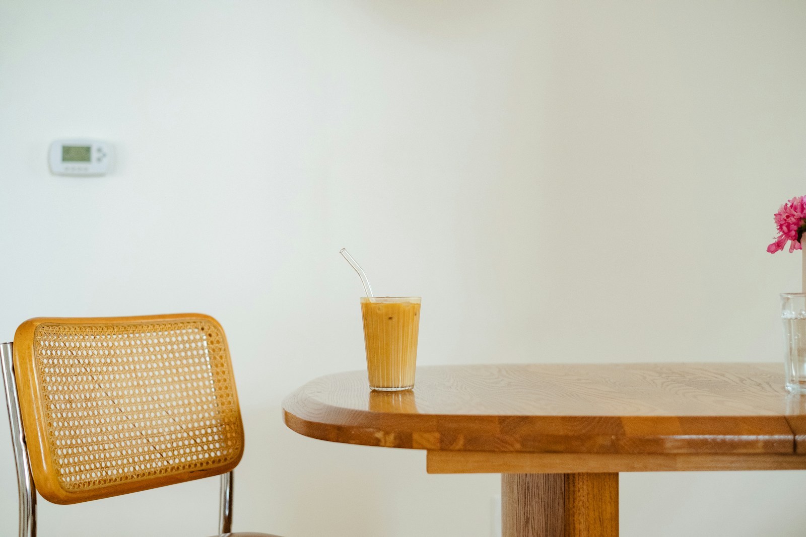 Fauteuil en cannage et table basse en verre à piètement fin dans un salon clair.