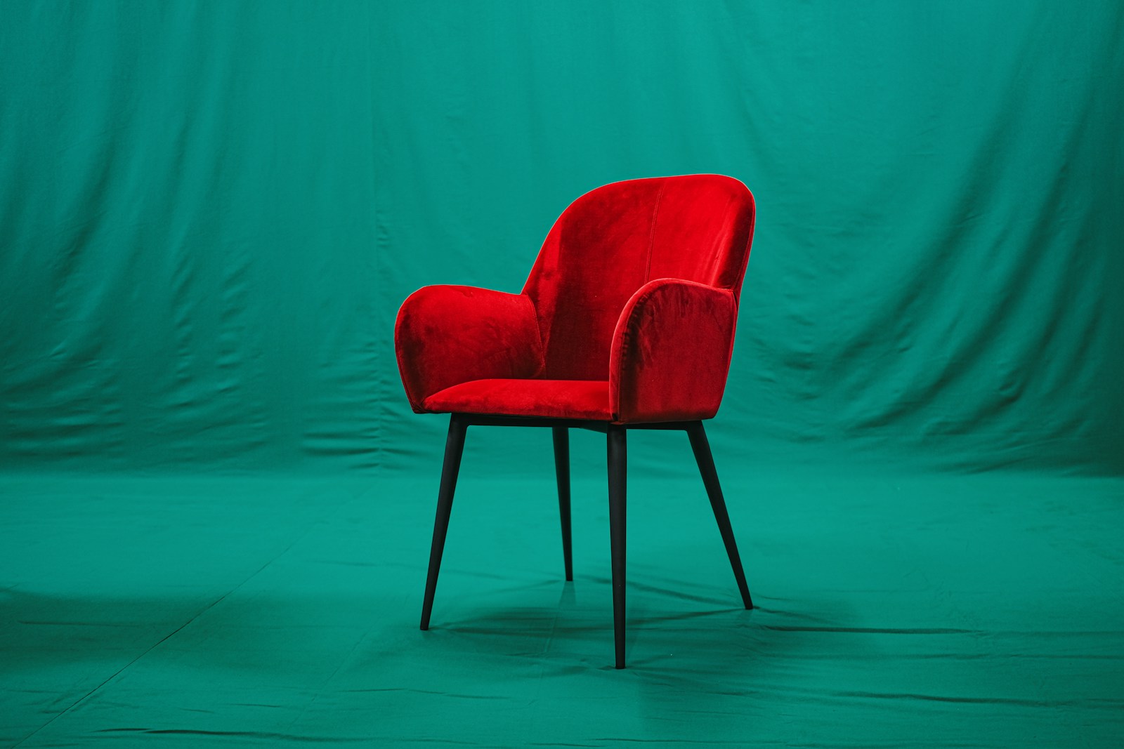 Fauteuil rouge vif devant un mur vert soutenu, contraste difficile.