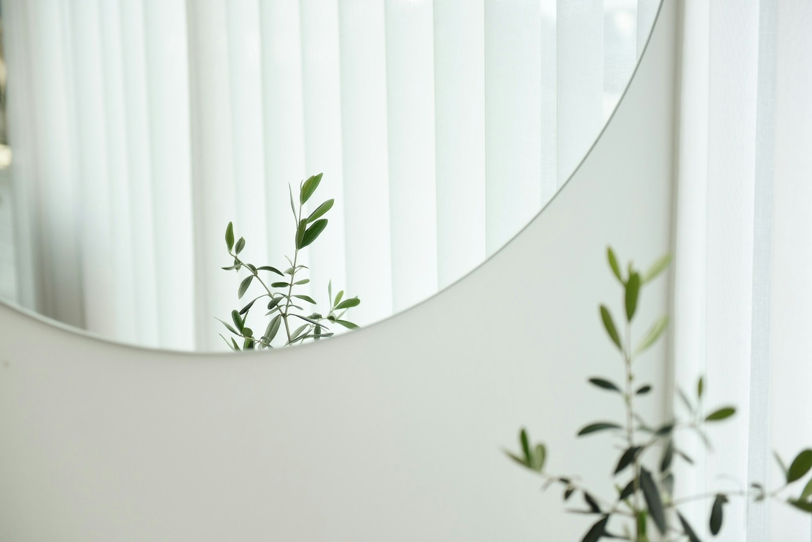 Grand miroir rond placé face à la fenêtre, renvoyant la lumière naturelle.