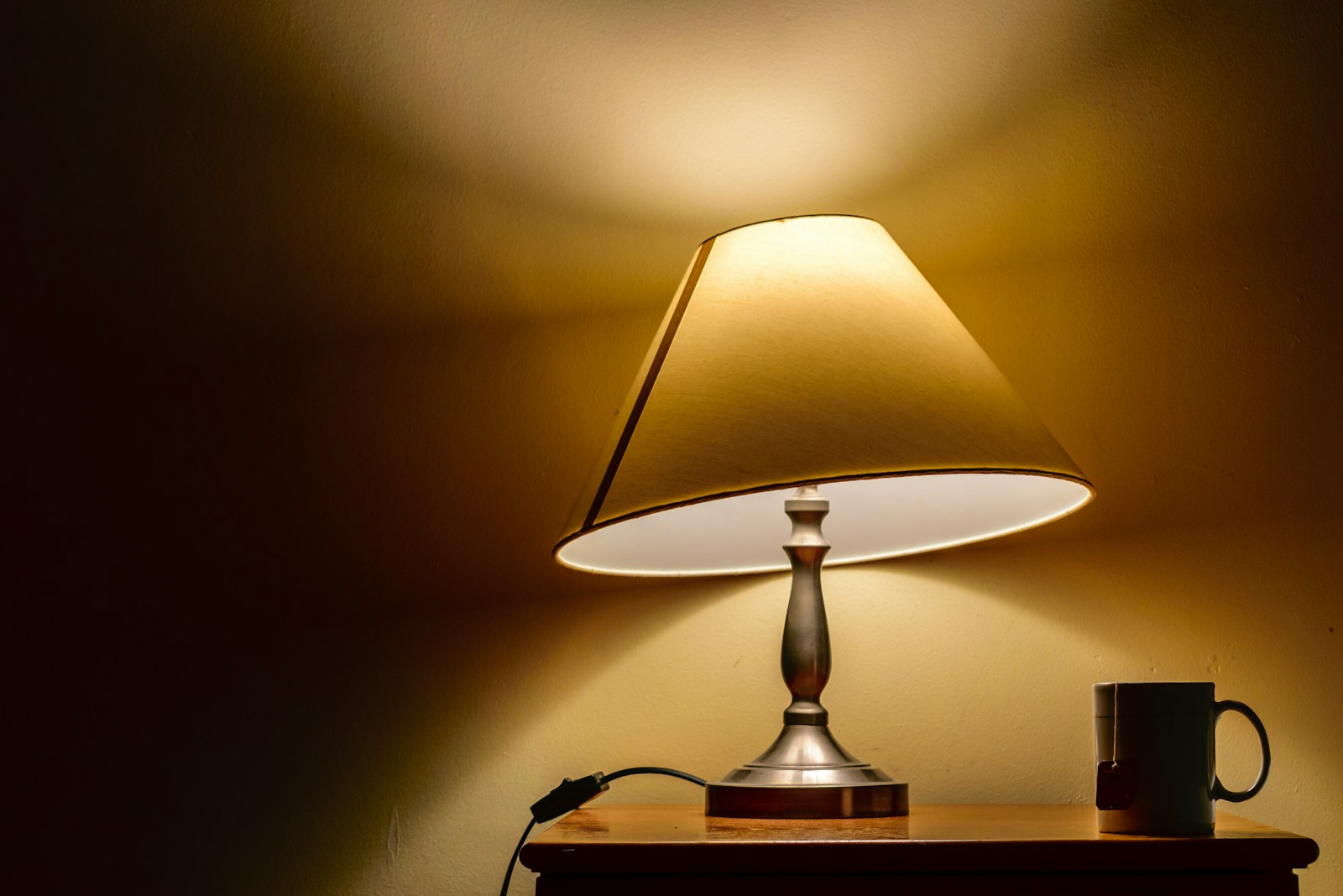 Lampe de bureau orientable en laiton posée sur un plateau en bois, lumière chaude.