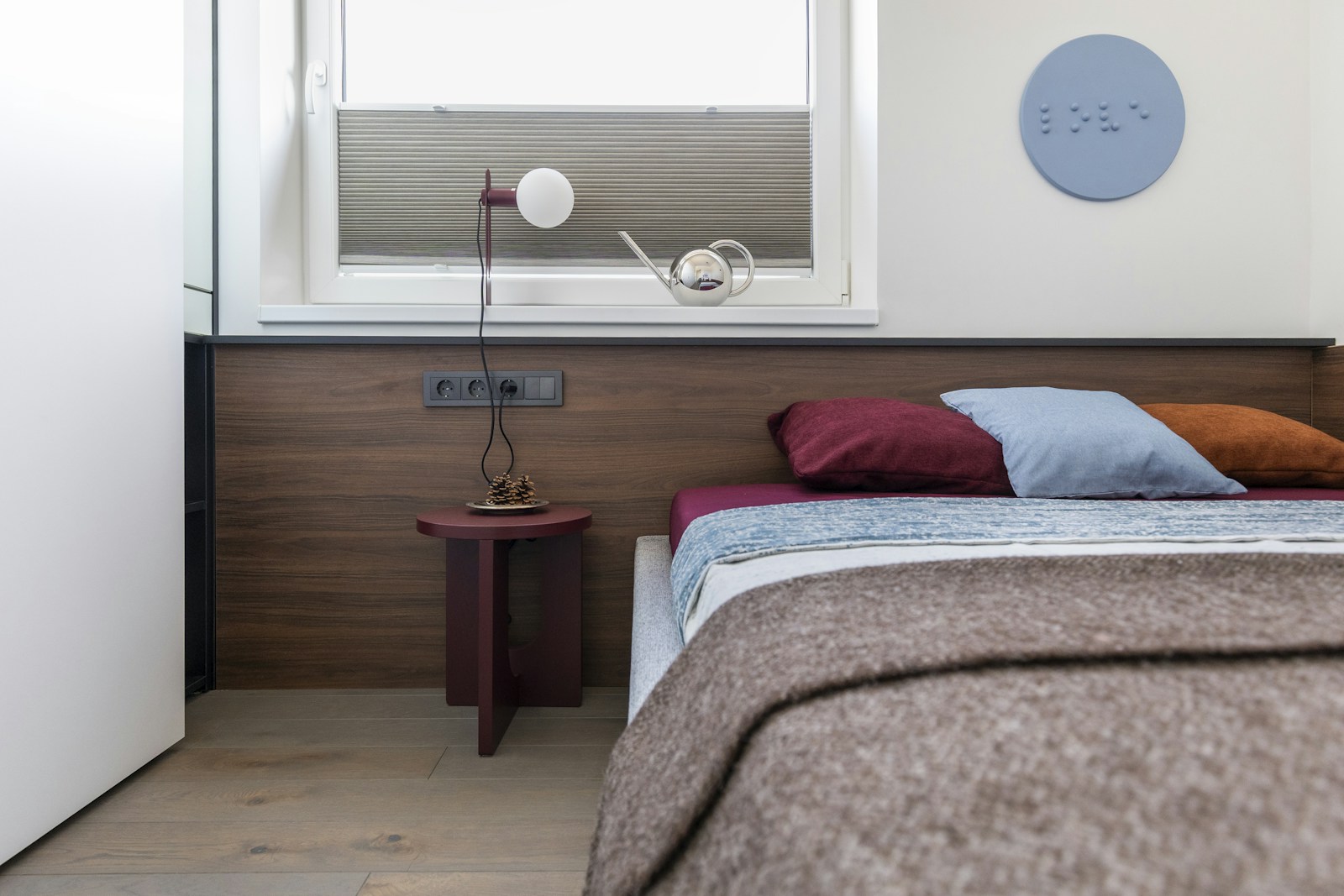 Lit posé en travers d'une petite chambre, avec un chevet en bois.