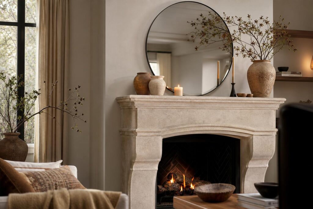 Manteau de cheminée en pierre décoré d'un miroir, de vases en terre cuite et de bougies dans un salon chaleureux.