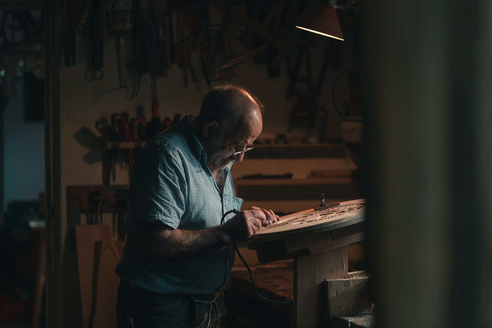 Menuisier rabotant un tasseau de bois dans son atelier.