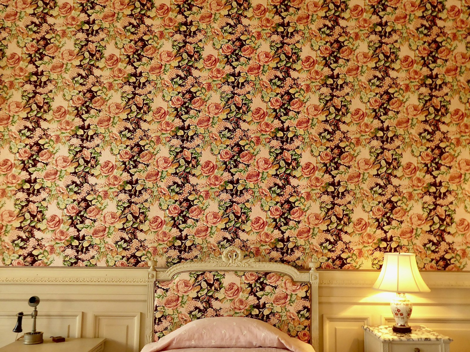 Mur de chambre habillé d'un papier peint à motif floral derrière le lit.