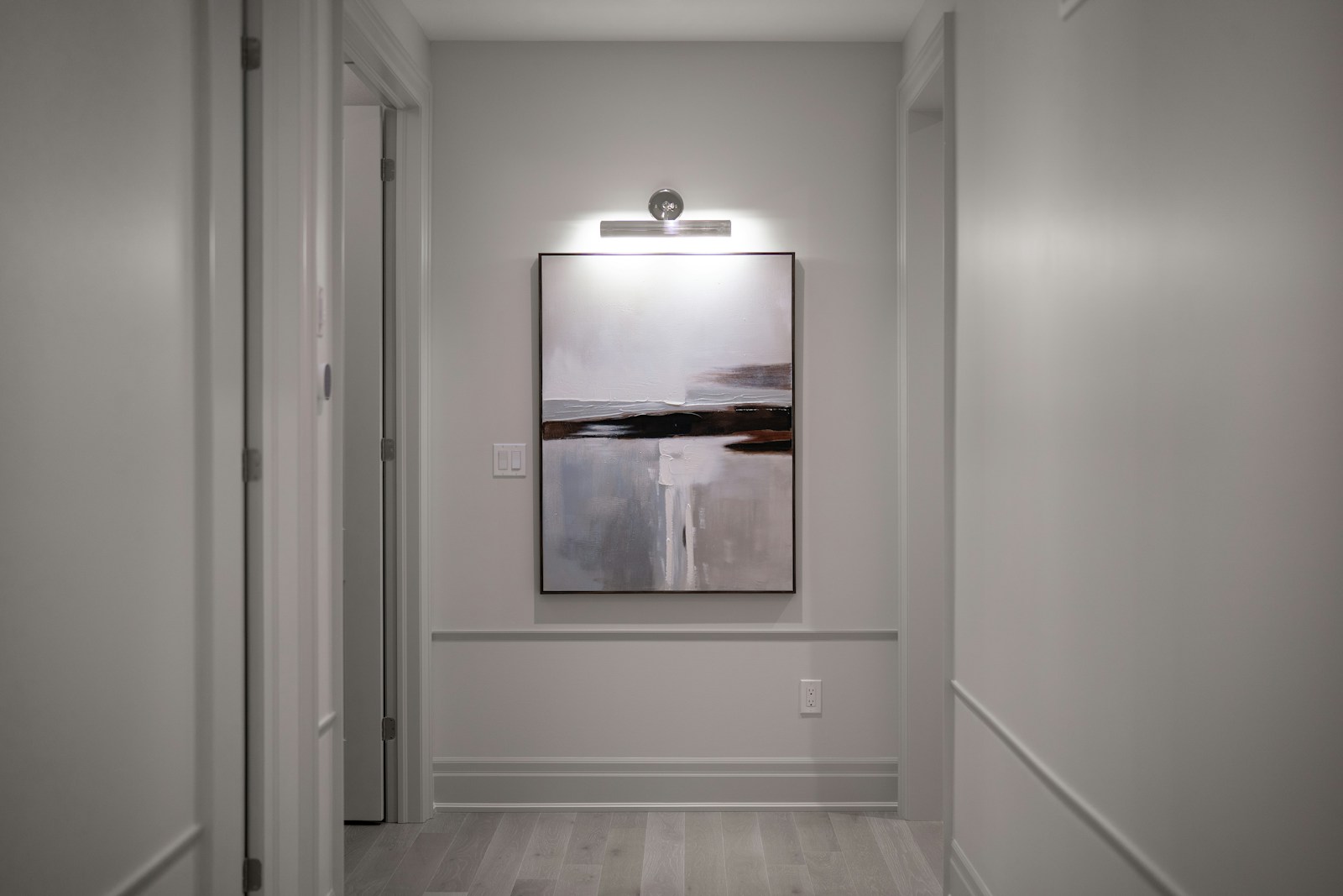 Mur de couloir peint dans un beige lin chaud, éclairé par une applique.
