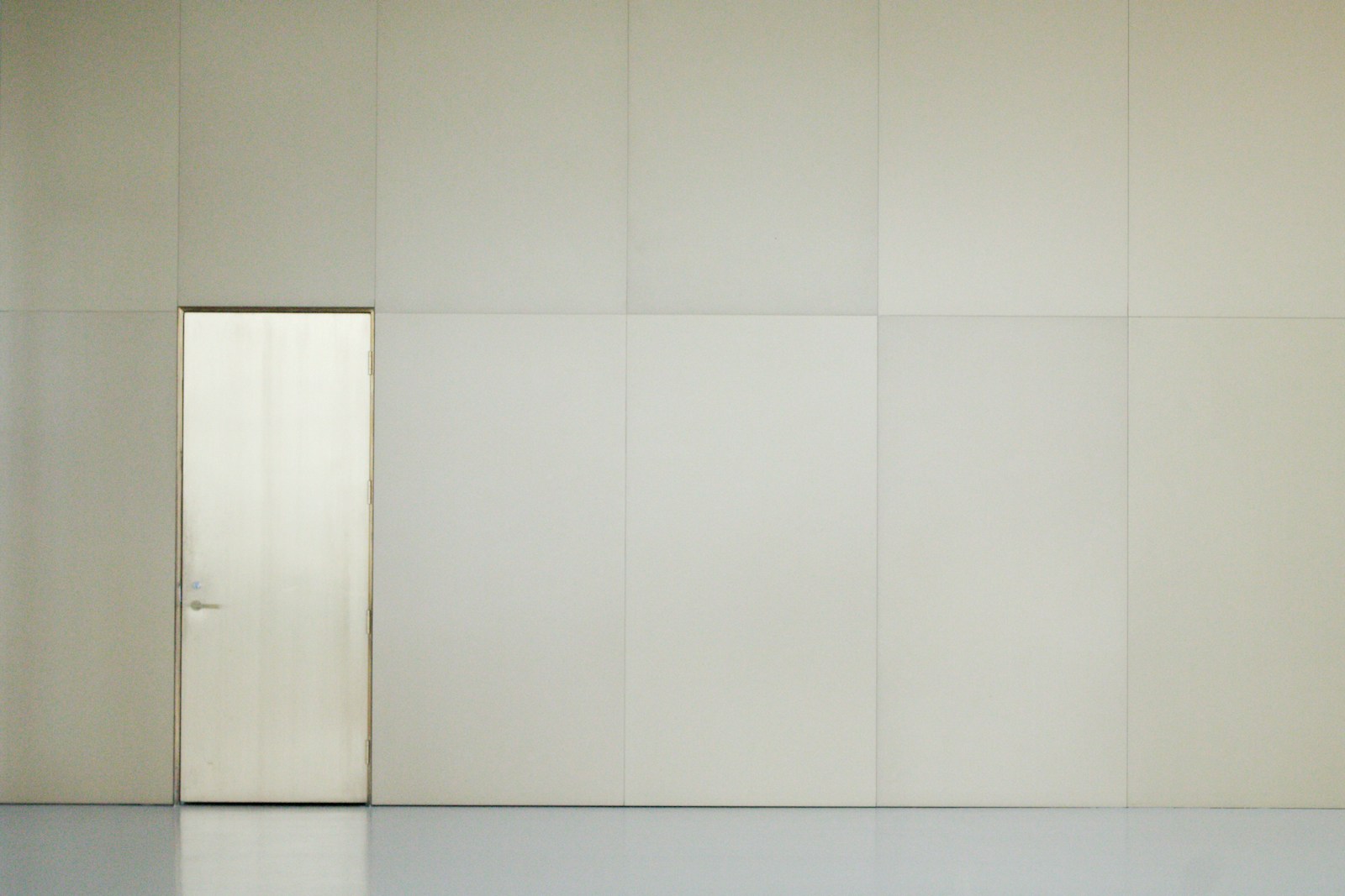 Mur et porte peints en beige mat, sans rupture de brillance.