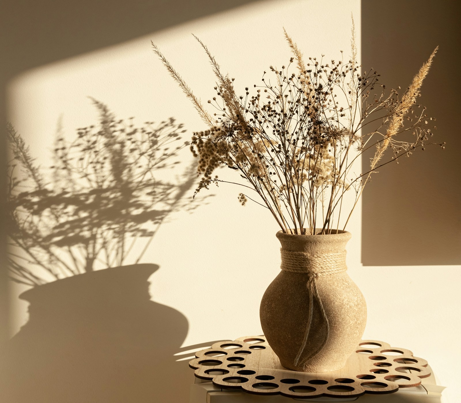 Panier en rotin et vase en céramique devant un mur enduit texturé