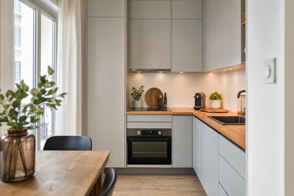 Petite cuisine compacte avec plan de travail en bois, électroménager encastré et rangements montant jusqu'au plafond.