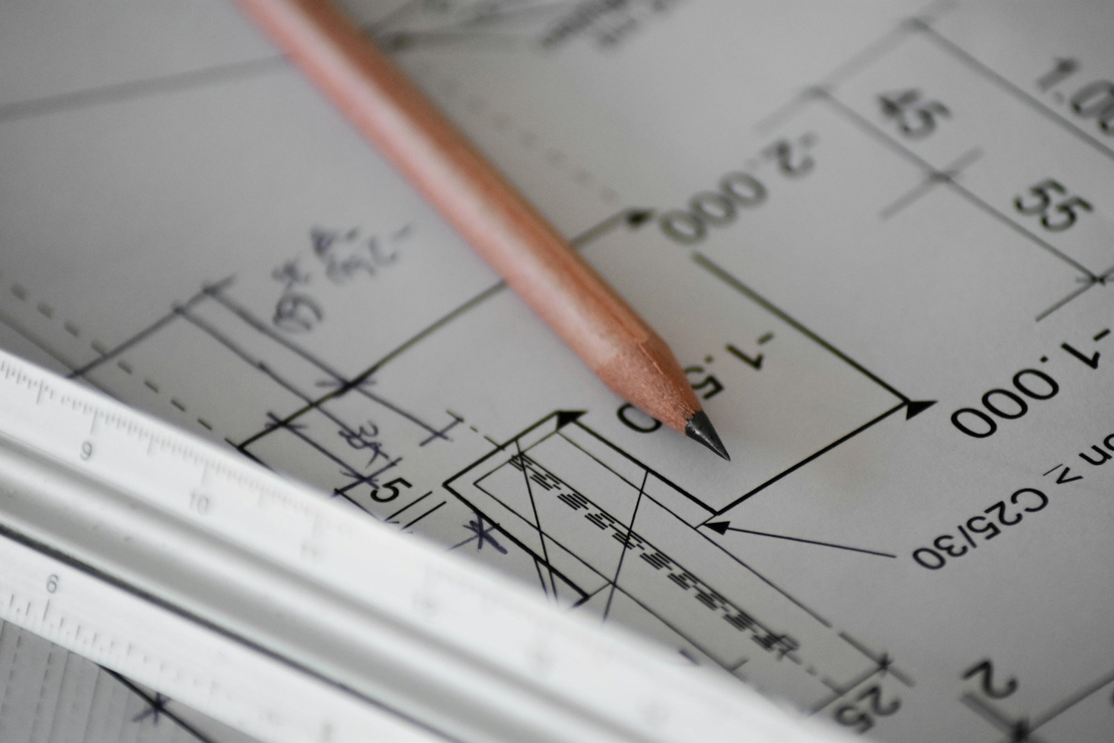 Plan d'architecte au crayon et règle posés sur une table de travail.