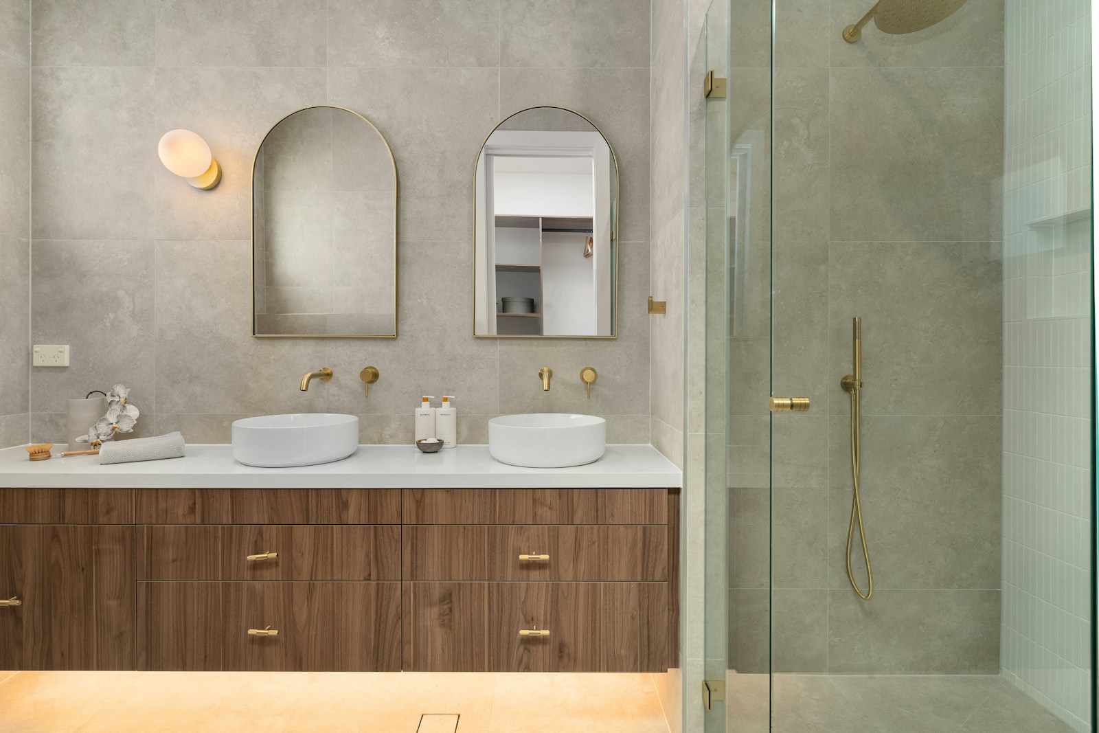 Robinetterie en laiton et meuble vasque en bois dans une petite salle de bain