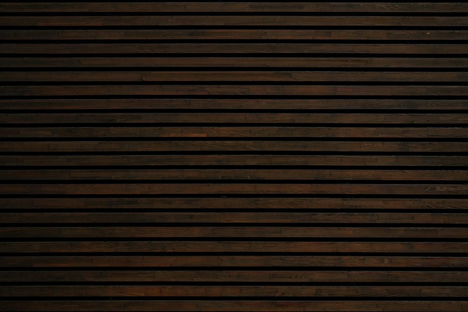 Séjour aux poutres de bois apparentes laissées brutes, mur de pierre en fond.