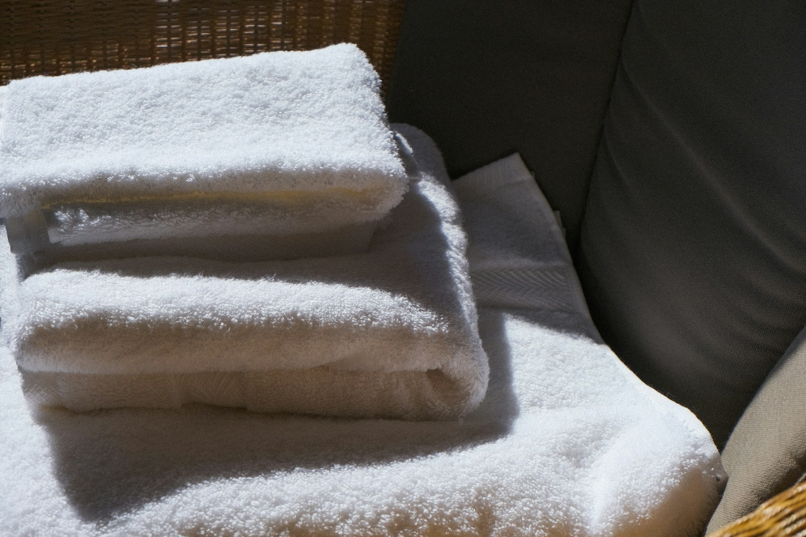 Serviettes en lin, panier en rotin et petite plante sur une étagère de salle de bain
