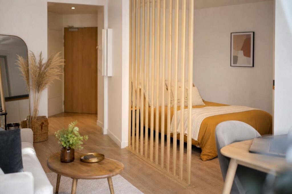 Studio de 30 m² avec coin nuit séparé par une cloison ajourée en bois et lumière naturelle.