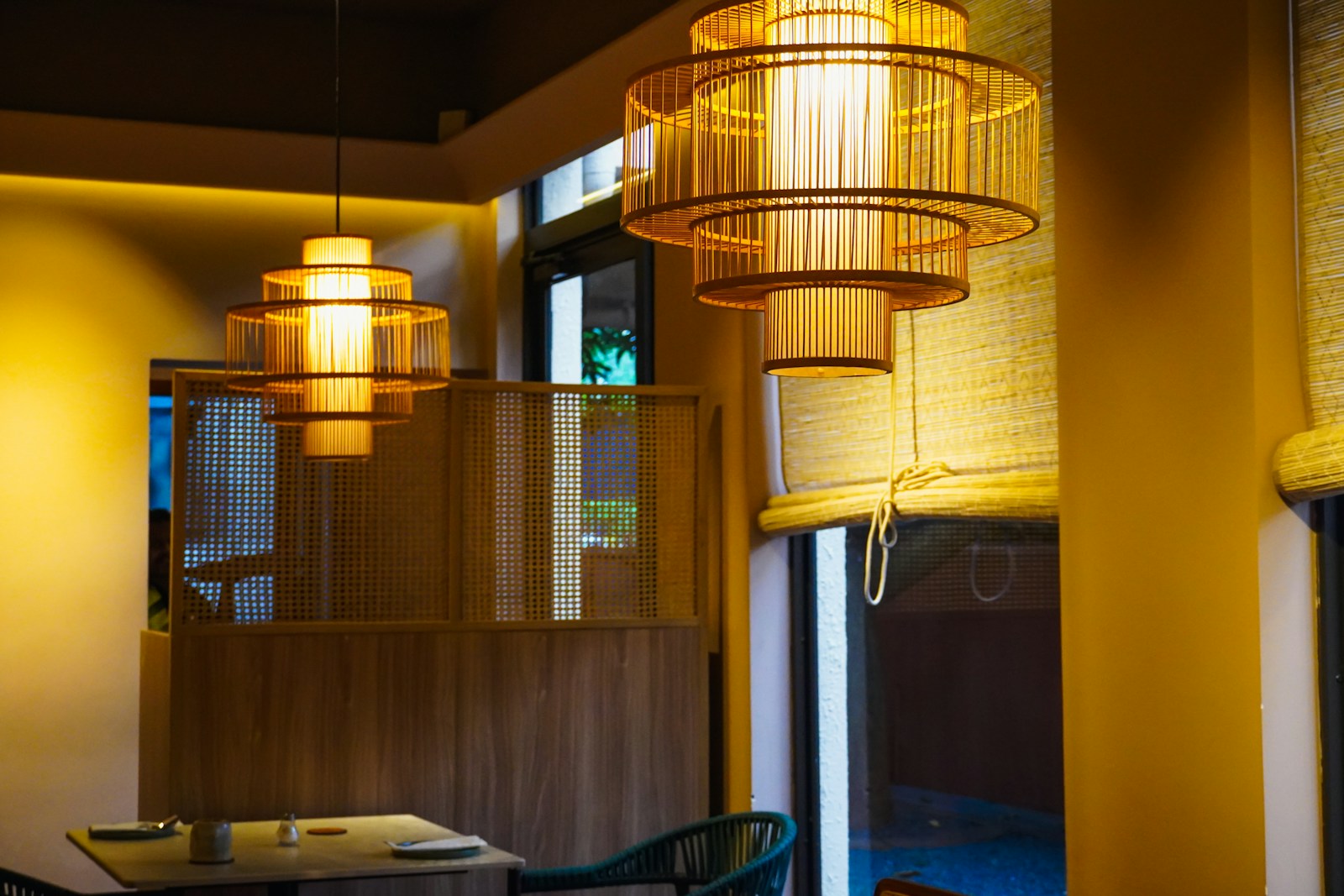 Suspension en rotin au-dessus d'une petite table, créant un îlot de lumière.