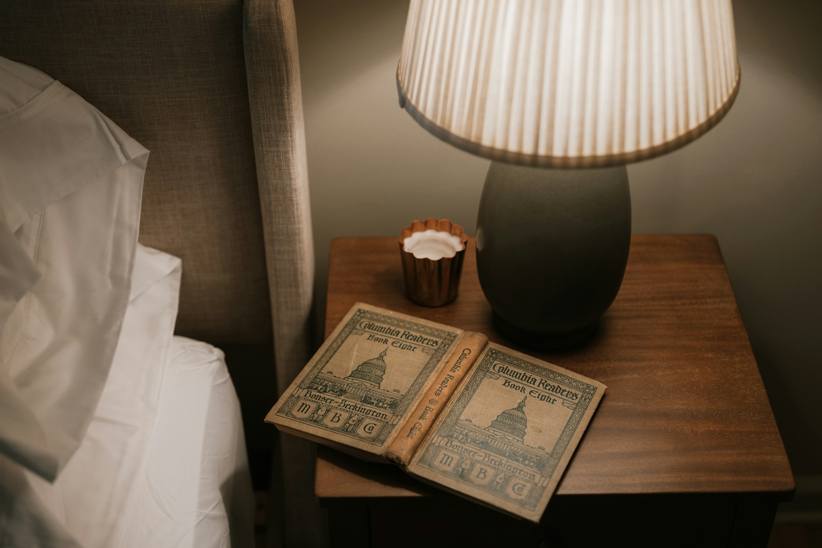 Table de chevet en bois patiné et lampe en laiton vieilli dans une chambre.