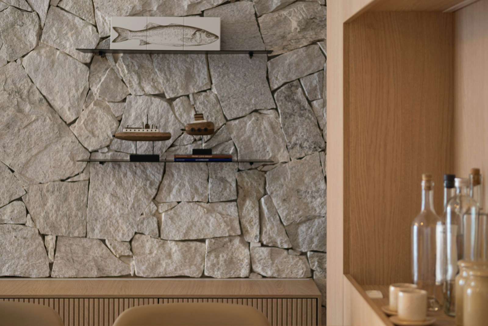 Table en chêne brut devant un mur de pierre : deux matières franches en contraste.