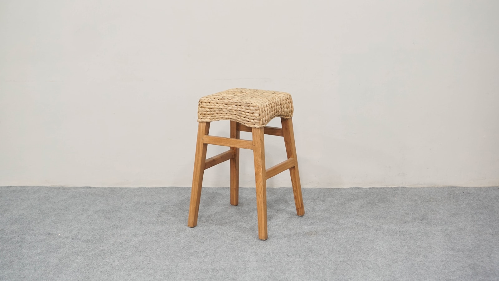 Tabouret de bar en rotin tressé devant un plan en bois clair.