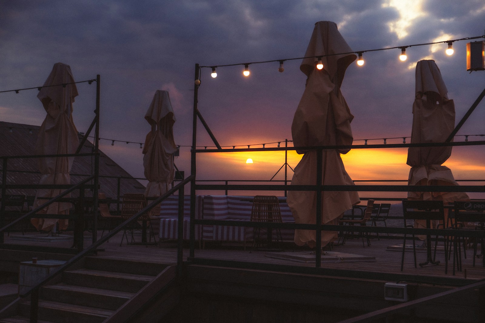 Terrasse à la tombée du jour éclairée par plusieurs petites sources de lumière chaude.