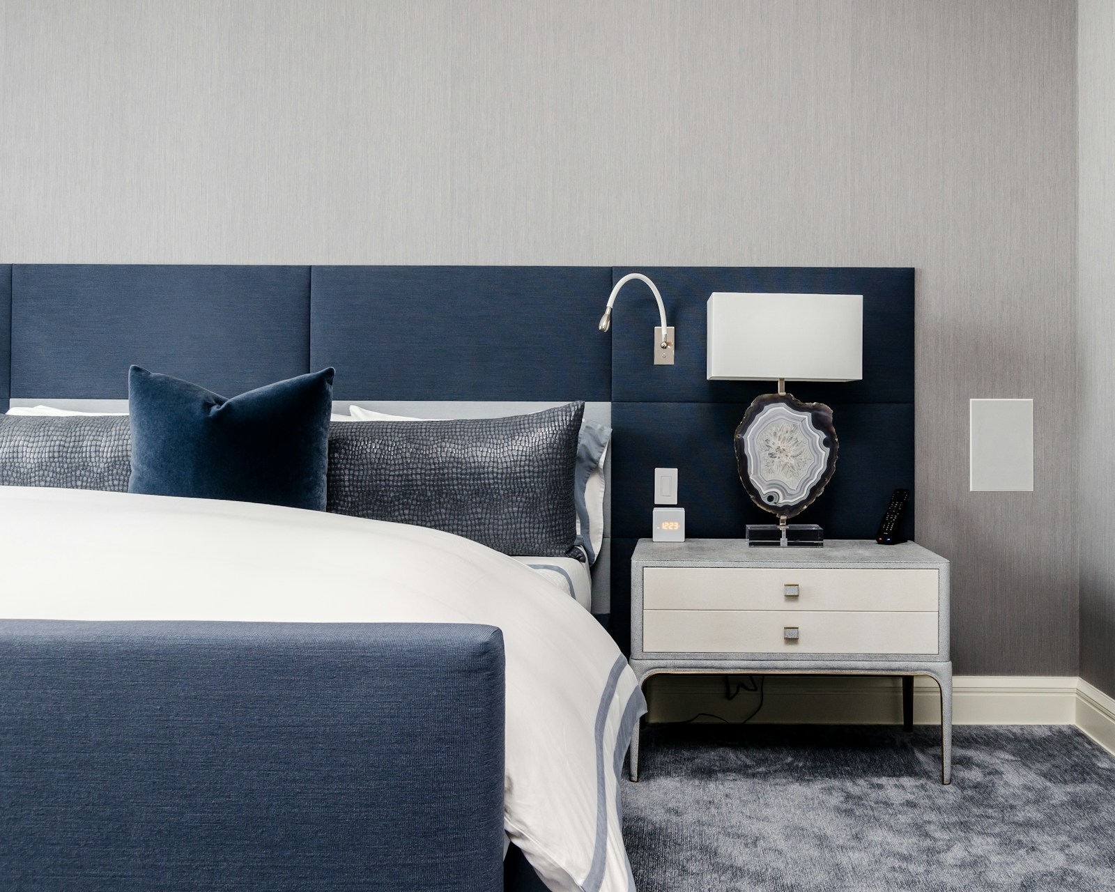 Tête de lit capitonnée en velours dans une chambre à l'éclairage doux.