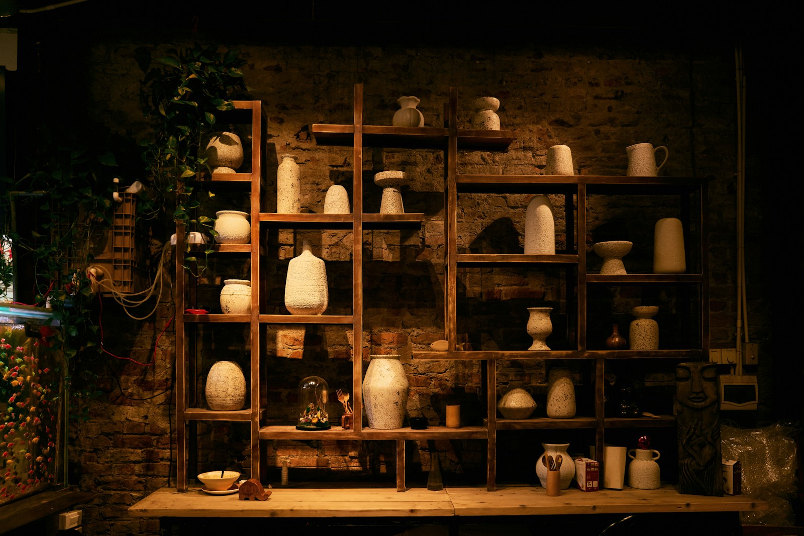 Vases en céramique artisanale alignés sur une étagère en bois, points de chaleur d'un intérieur épuré.