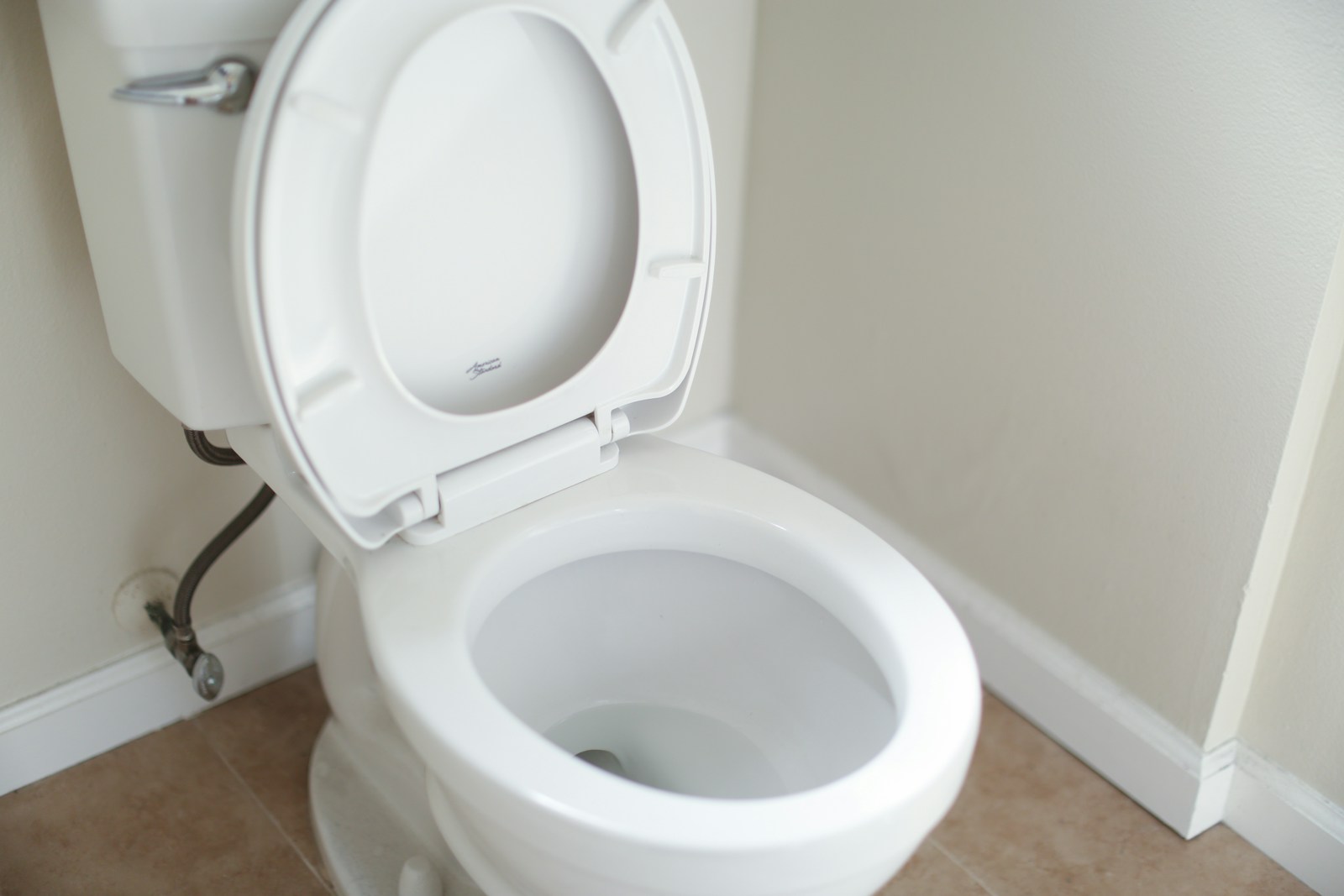 WC au sol classique en céramique blanche avec réservoir attenant.