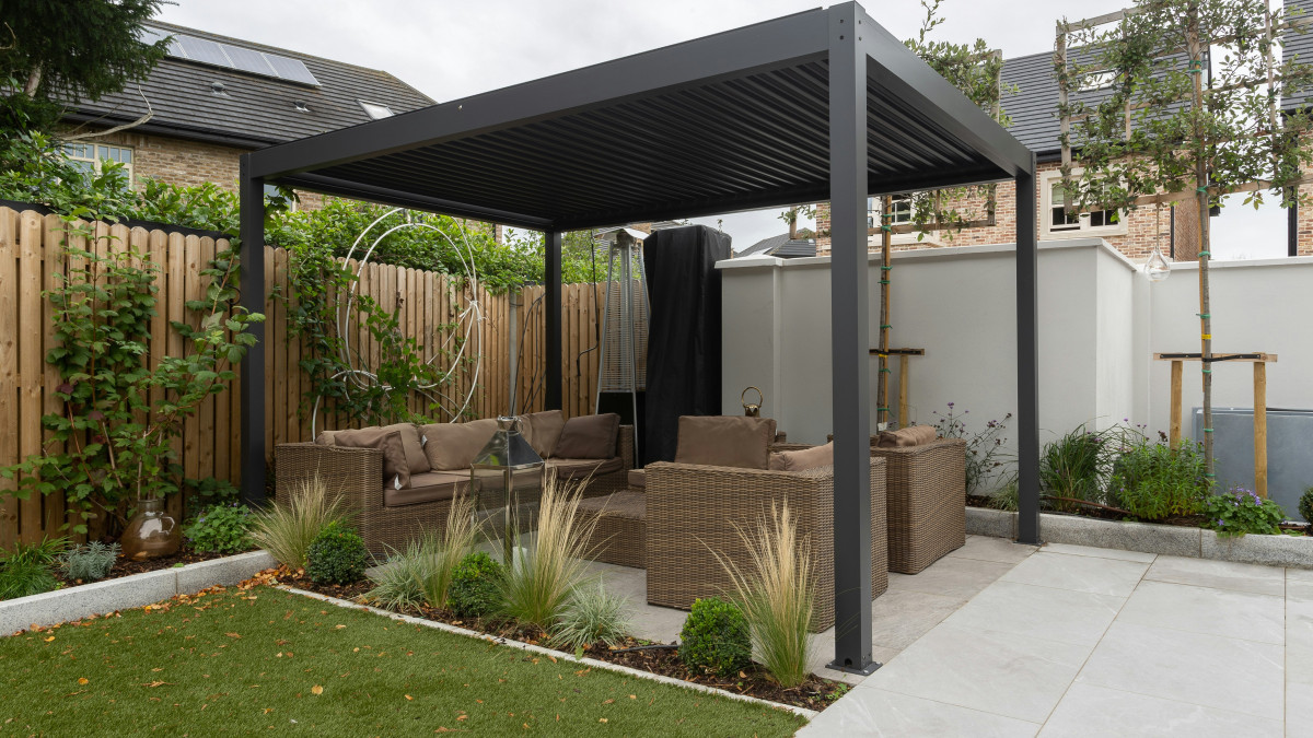 Une pergola bioclimatique est installée dans le jardin d'une maison.
